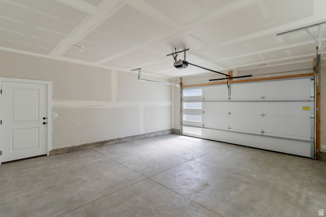 248 West 2920th Street South Logan, UT 84321 - Photo 26 of 47 Spacious garage featuring a concrete floor, overhead lighting, an automatic garage door opener, and a panel door with black hardware