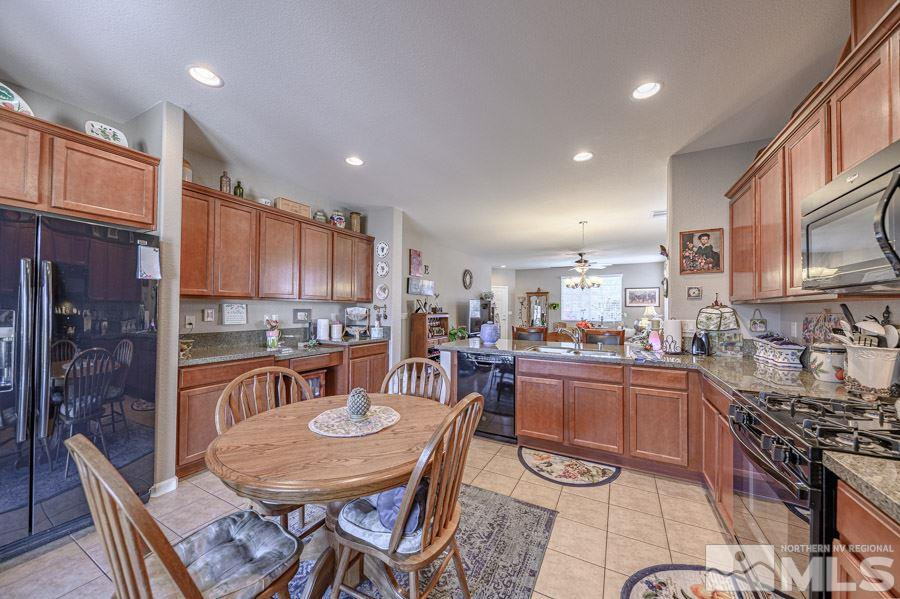 11048 Colton Drive Reno, NV 89521 - Photo 13 of 23 a kitchen with stainless steel appliances granite countertop a stove top oven a sink a dining table and chairs