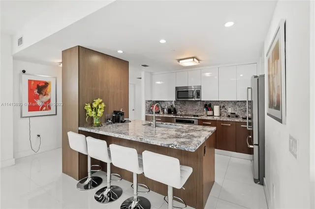 a kitchen with stainless steel appliances granite countertop a sink and a refrigerator