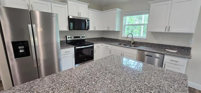 a kitchen with stainless steel appliances granite countertop a refrigerator sink and stove