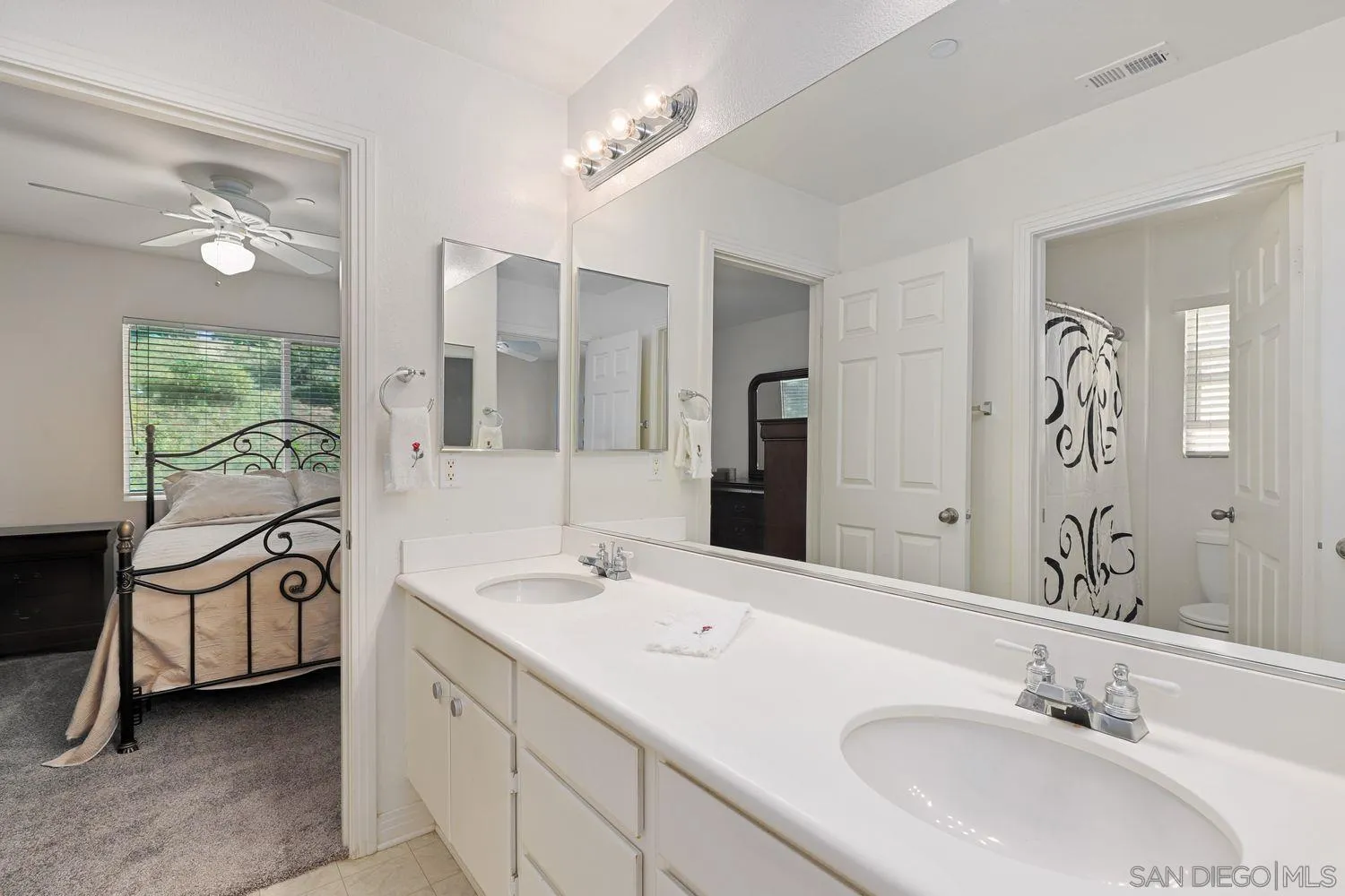 554 Poets Square Fallbrook, CA 92028 - Photo 18 of 28 a bathroom with a double vanity sink a mirror and a bathtub next to a window