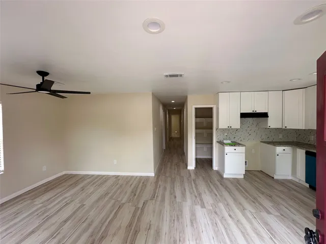 a open kitchen with white cabinets and wooden floor