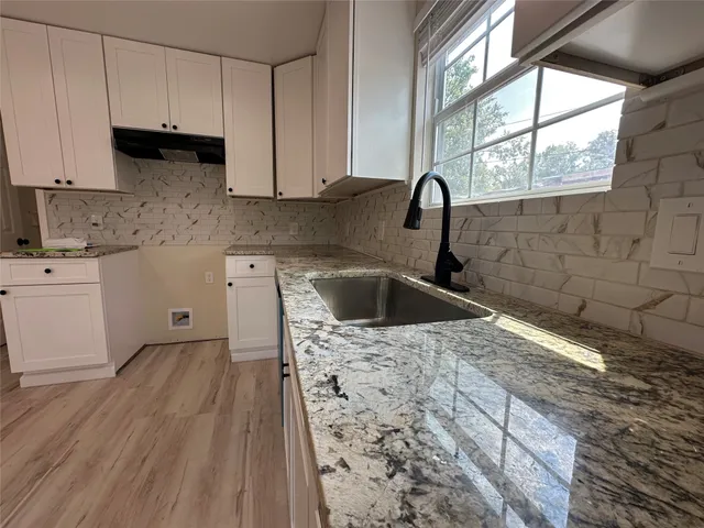 a kitchen with granite countertop a sink a stove and cabinets