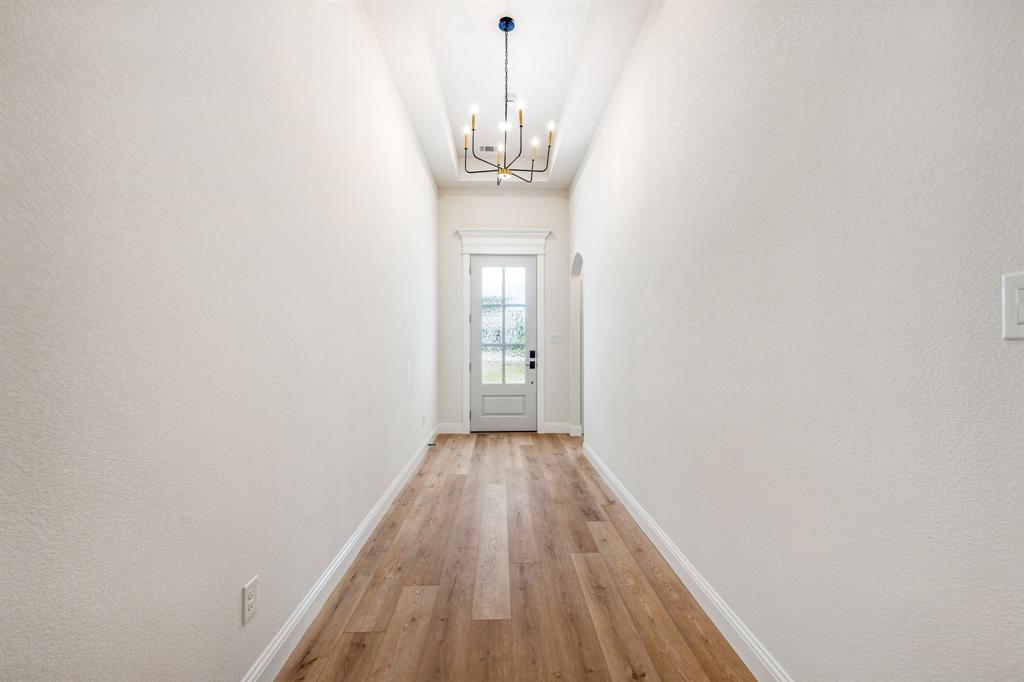 122 John Street Aledo, TX 76008 - Photo 18 of 33 a view of a hallway with wooden floor and a chandelier