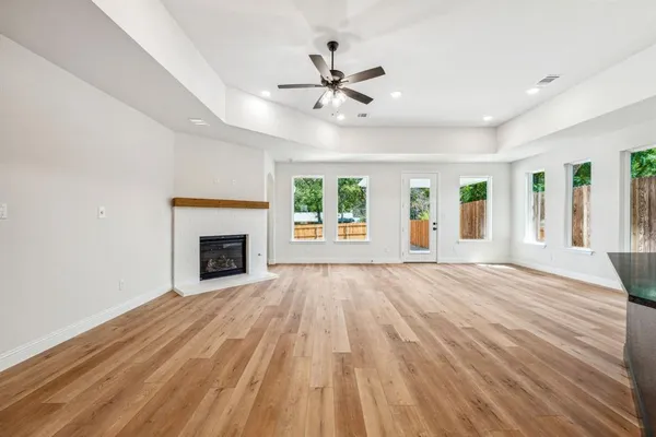 a view of an empty room with wooden floor fireplace and a window