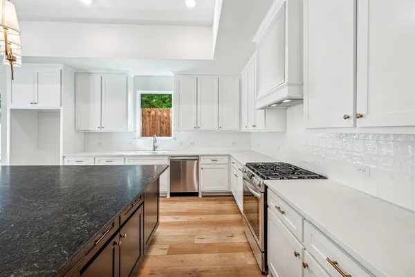 a kitchen with granite countertop a sink stove and cabinets