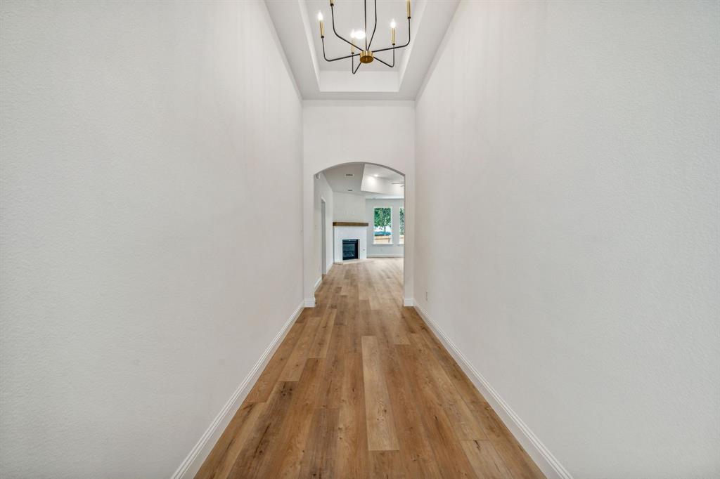 122 John Street Aledo, TX 76008 - Photo 32 of 33 a view of a hallway with wooden floor and a chandelier