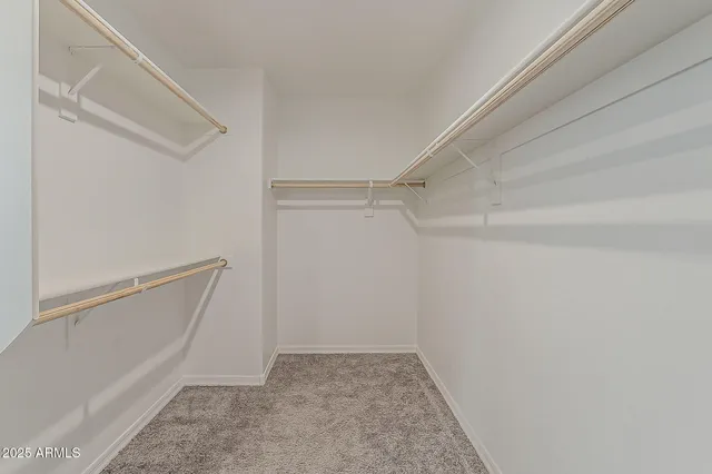 a view of an empty room with chandelier fan and fire place