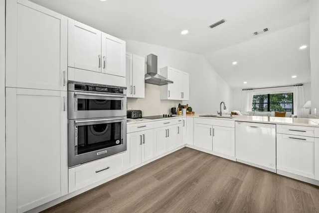 a kitchen with granite countertop white cabinets and white appliances