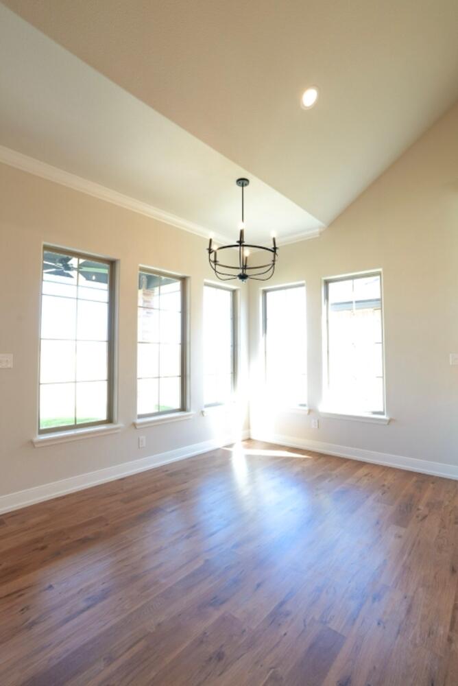 712 East 19th Street Wolfforth, TX 79382 - Photo 6 of 23 an empty room with wooden floor and windows