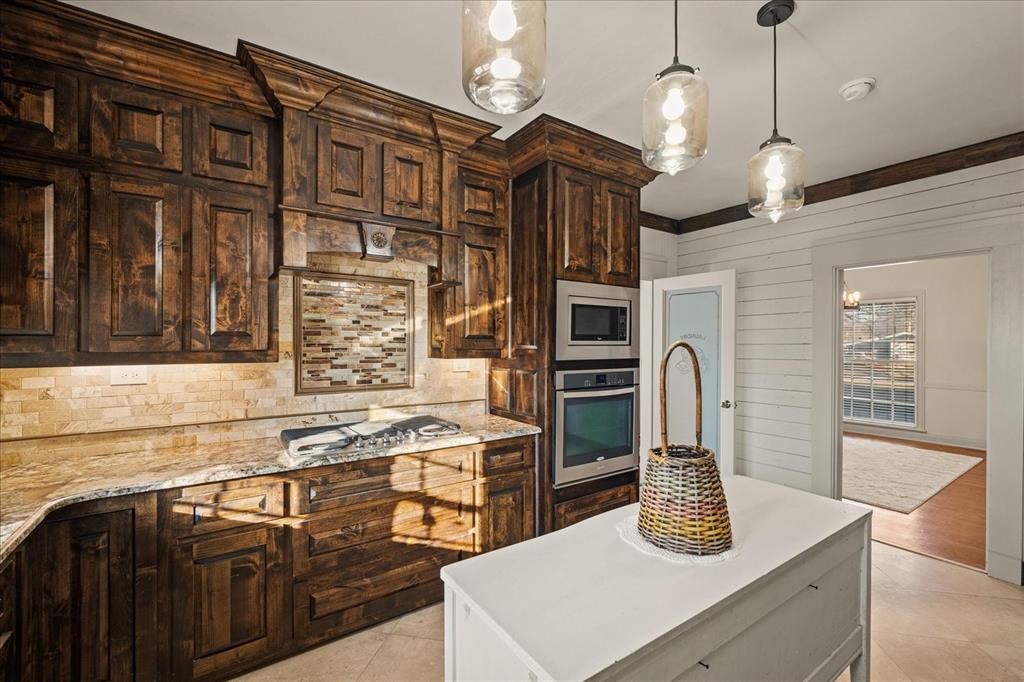 601 North Main Street Leonard, TX 75452 - Photo 11 of 34 Kitchen featuring a kitchen island, hanging light fixtures, stainless steel appliances, light stone counters, and decorative backsplash