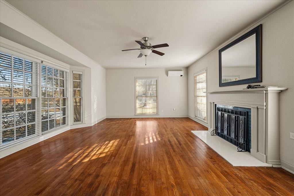 601 North Main Street Leonard, TX 75452 - Photo 7 of 34 Unfurnished living room with hardwood / wood-style flooring, a ceiling fan, and a fireplace with flush hearth