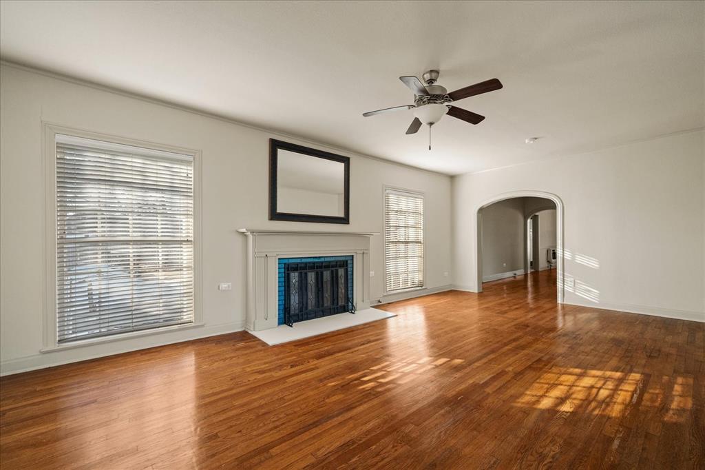 601 North Main Street Leonard, TX 75452 - Photo 8 of 34 Unfurnished living room featuring a ceiling fan, wood finished floors, arched walkways, and a fireplace with flush hearth