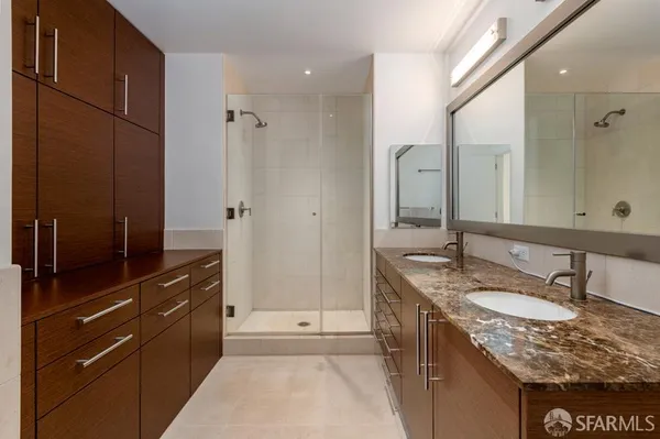 a bathroom with a granite countertop sink a mirror and shower