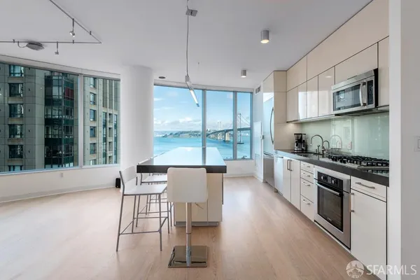 a kitchen with stainless steel appliances granite countertop a stove top oven a sink a dining table and chairs with wooden floor