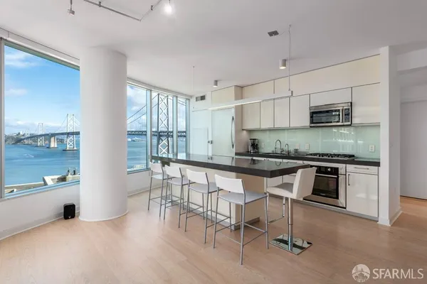 a kitchen with stainless steel appliances granite countertop a stove top oven a sink a dining table and chairs with wooden floor