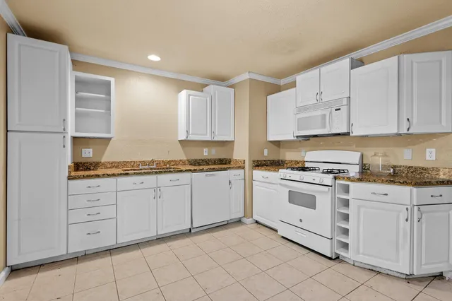 a kitchen with granite countertop white cabinets and white appliances