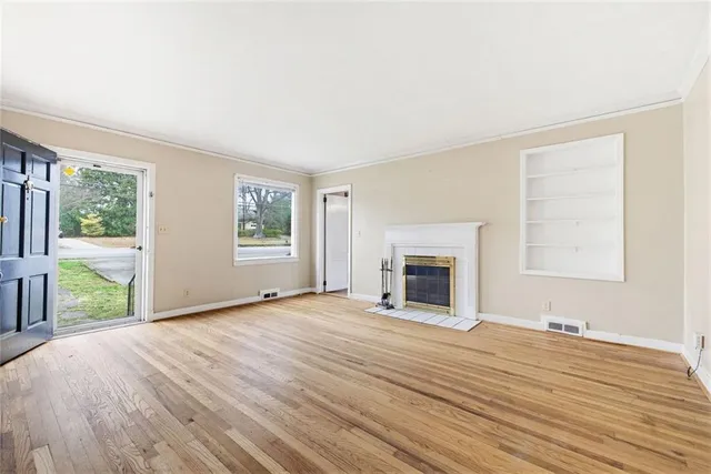 a view of an empty room with a window and fireplace