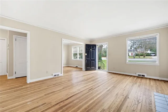 an empty room with wooden floor and windows