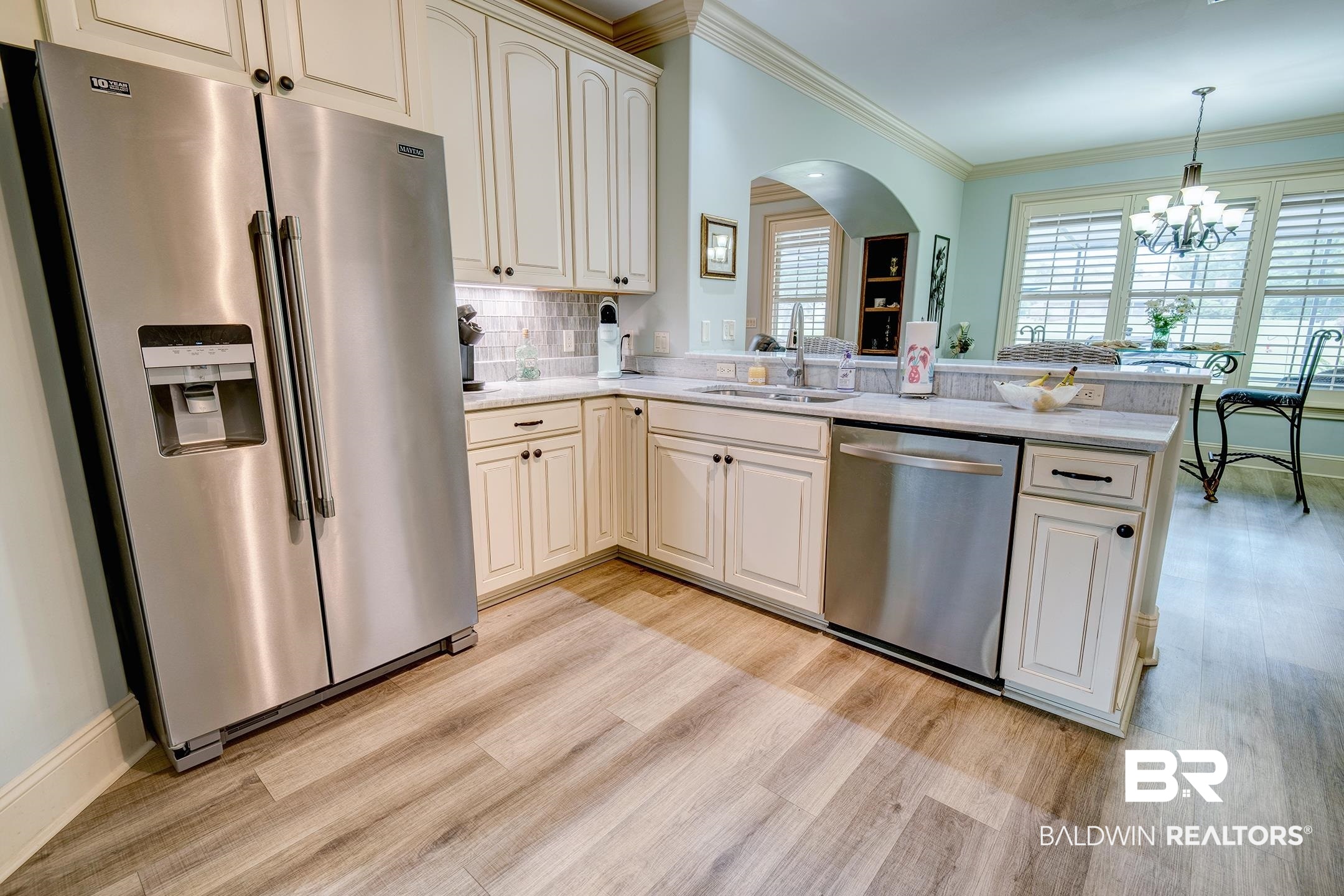 9357 Lakeview Drive Foley, AL 36535 - Photo 32 of 68 Kitchen featuring light wood-finish flooring, white cabinetry with dark hardware, stainless steel appliances, and a light-toned countertop with a tiled backsplash