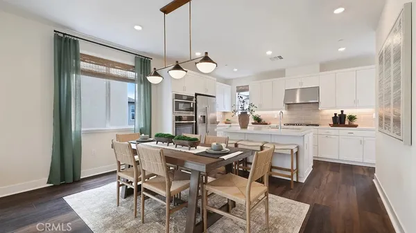 a kitchen with a dining table chairs and wooden floor