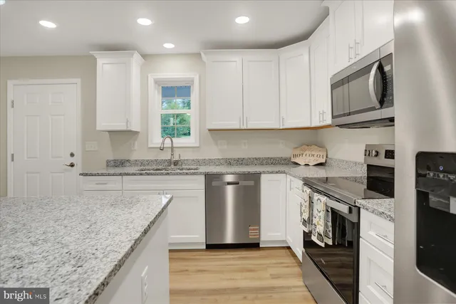 a kitchen with stainless steel appliances granite countertop a stove a sink and a microwave
