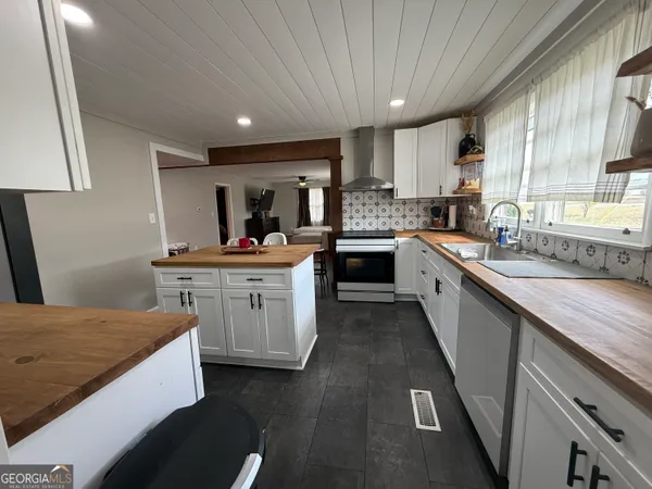 a kitchen with a sink dishwasher a stove a microwave oven and a dining table with wooden floor
