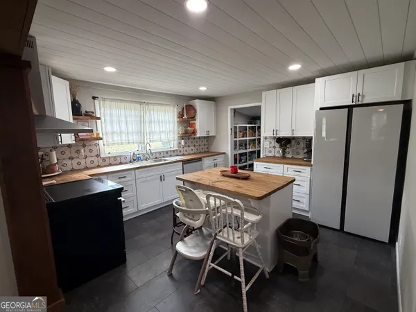 a kitchen with stainless steel appliances kitchen island granite countertop a refrigerator a stove a sink dishwasher and white countertops with wooden floor