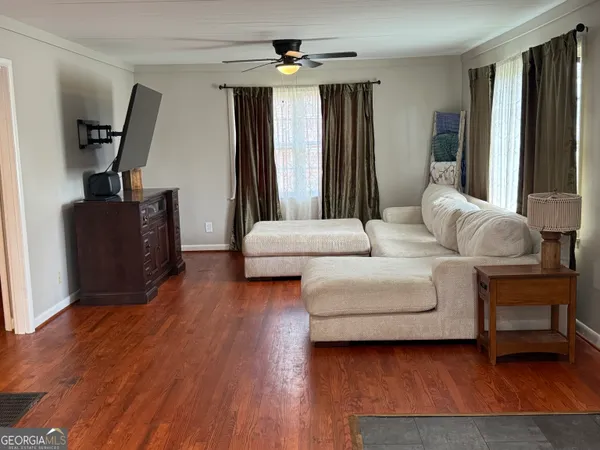 a view of an empty room with wooden floor and a window