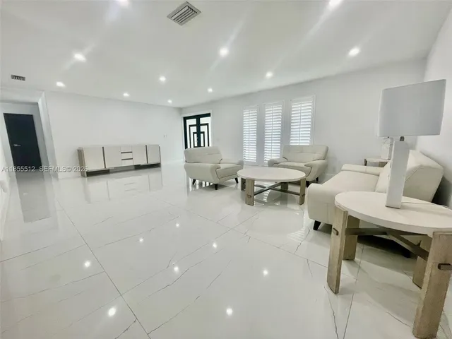 a living room with chairs and kitchen view