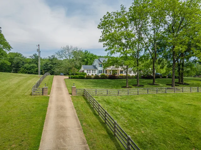 a front view of a house with a garden and trees