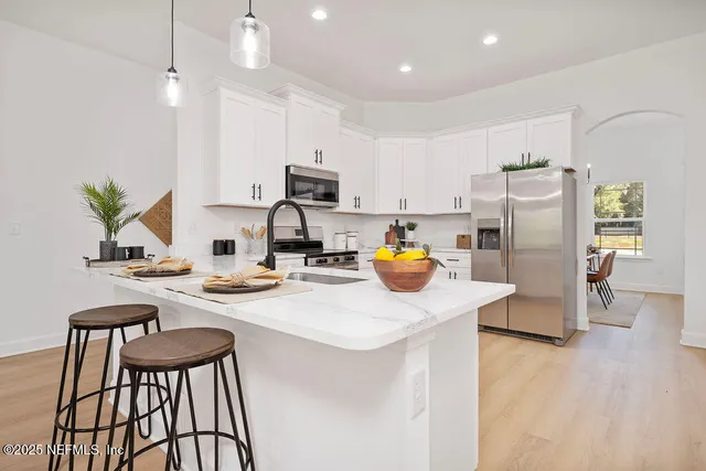 a kitchen with stainless steel appliances granite countertop a refrigerator a stove a sink dishwasher a dining table and chairs with wooden floor