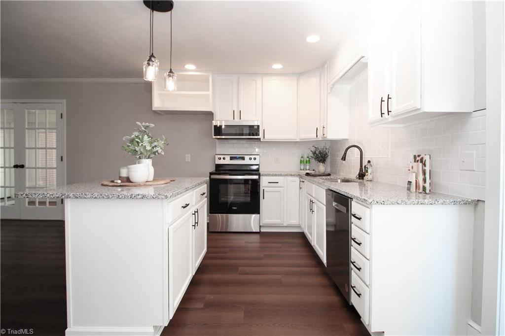 3705 Holts Chapel Road Greensboro, NC 27401 - Photo 11 of 33 Kitchen features new LVP flooring, slide in range, built in microwave, dishwasher, and granite countertops