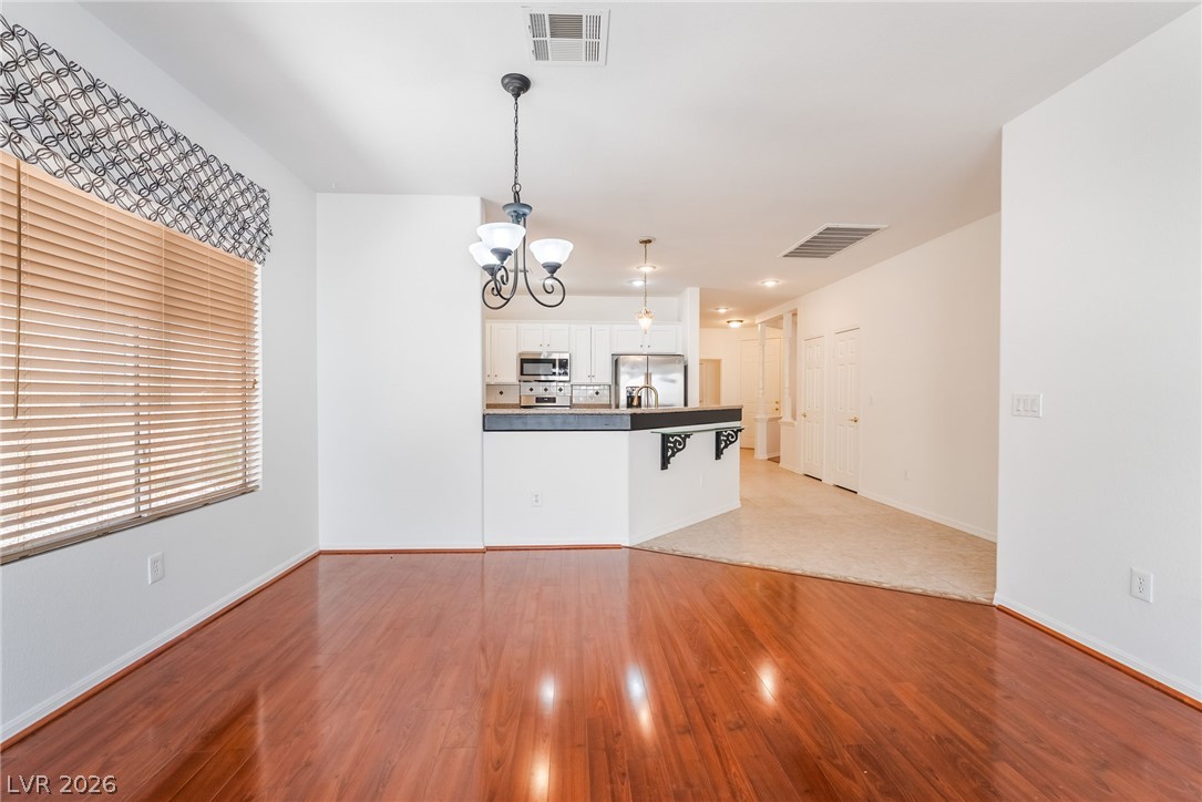 5389 Progresso Street Las Vegas, NV 89135 - Photo 14 of 41 Rich hardwood floors complement a well-lit living area, flowing into a practical kitchen space.