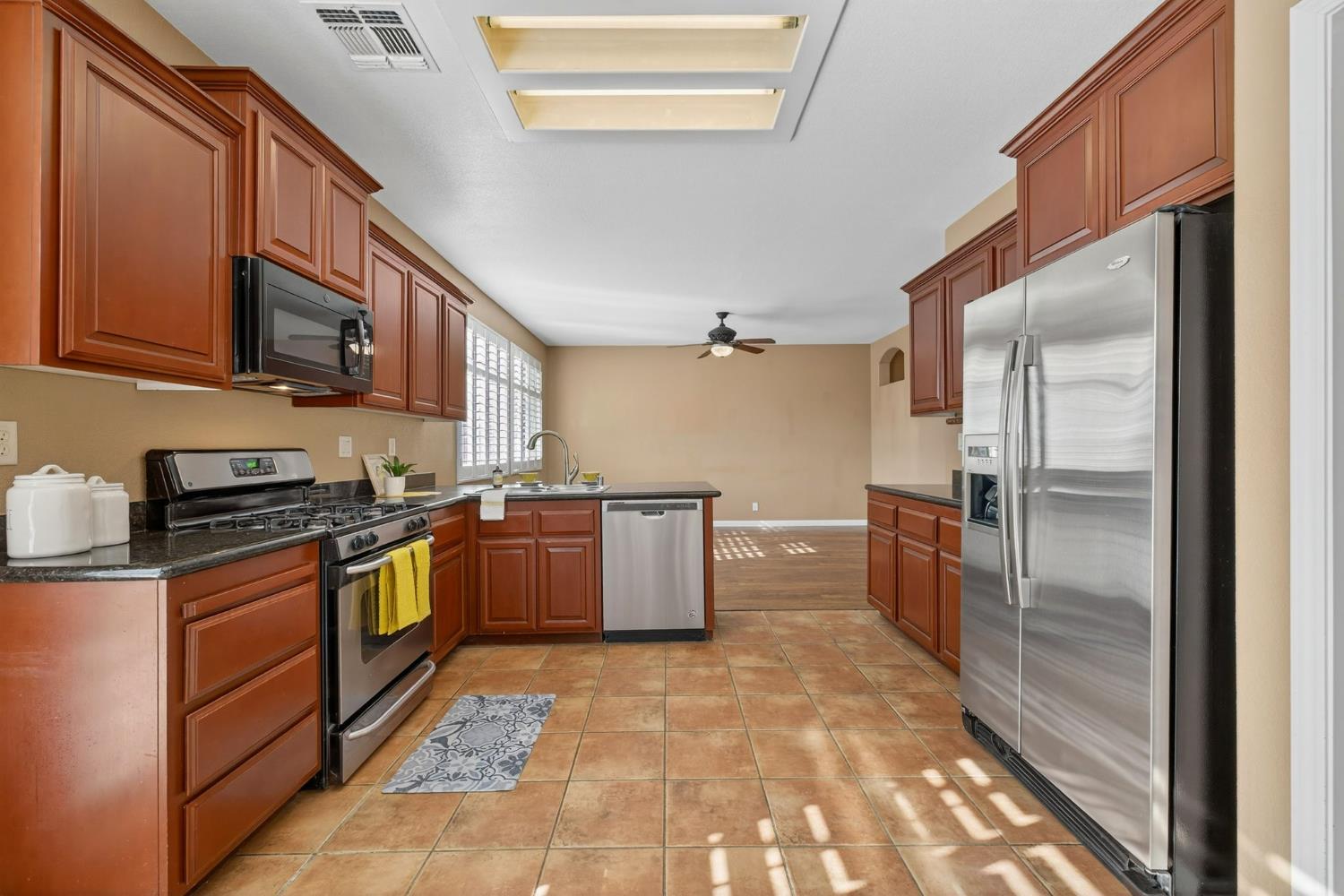 1716 Presidio Way Plumas Lake, CA 95961 - Photo 17 of 43 a kitchen with stainless steel appliances granite countertop a refrigerator a stove and a sink with wooden cabinets