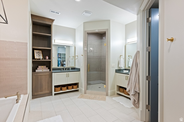 3 Carriagewood Cove, Unit 1088 Sandy, UT 84092 - Photo 58 of 79 Spacious bathroom featuring a glass-enclosed shower, dual vanity sinks with dark countertops, built-in shelving, and light tile flooring