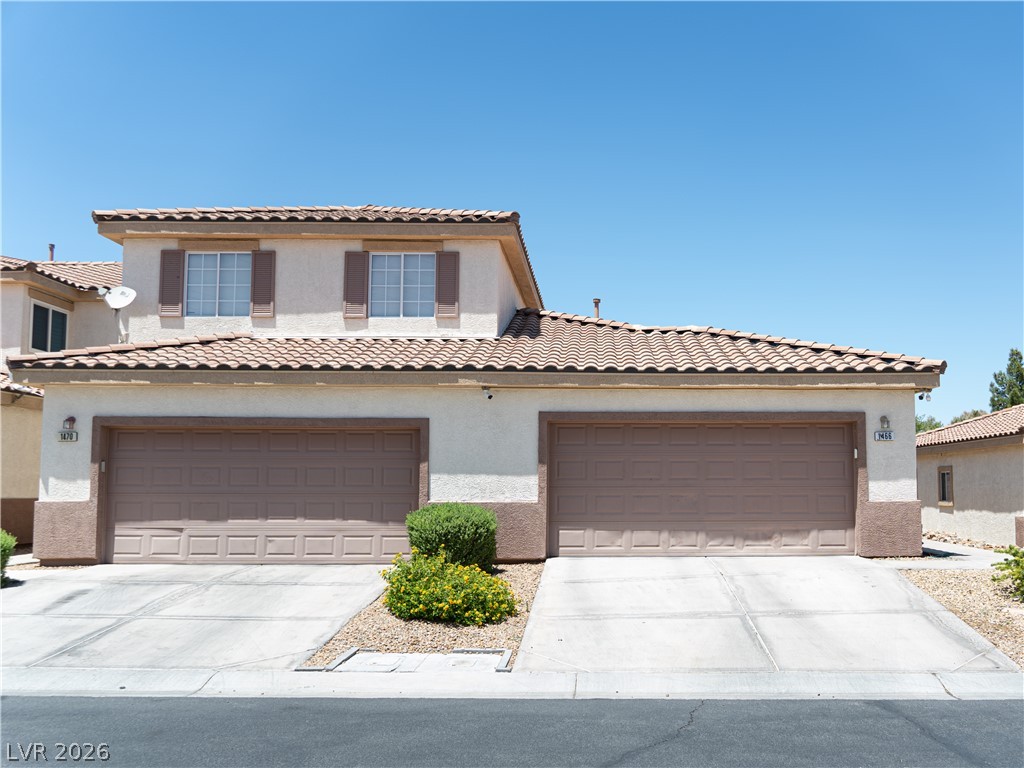 1466 Orange Jubilee Road Henderson, NV 89014 - Photo 2 of 15 A well-maintained facade features double garage doors and a classic tiled roof.