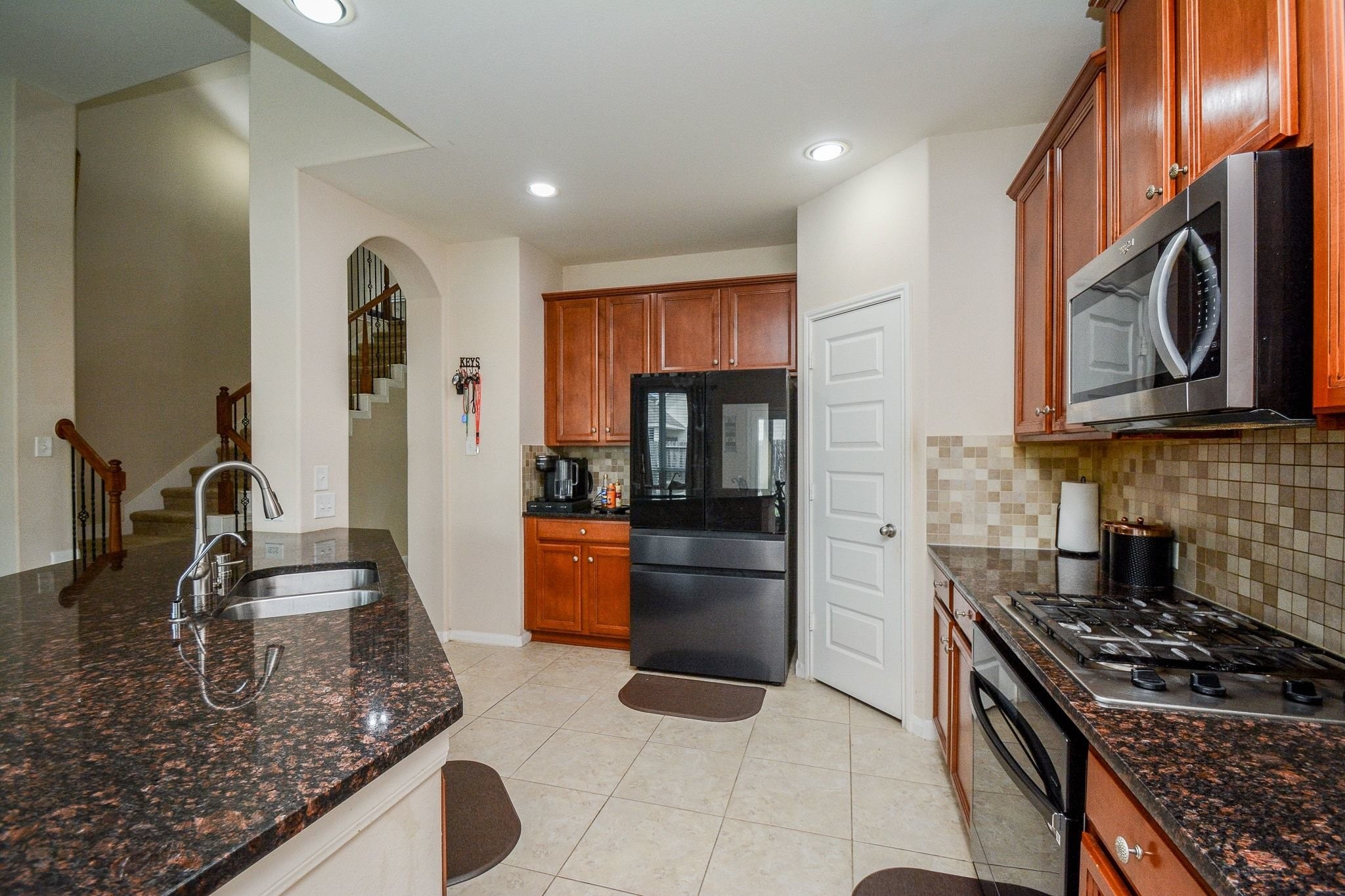 7046 Sliding Rock Circle Spring, TX 77379 - Photo 12 of 41 This modern kitchen boasts elegant granite countertops, sleek stainless steel appliances, and ample cabinetry for storage. Perfect for culinary enthusiasts, it features a functional layout with a spacious island and stylish tile backsplash.