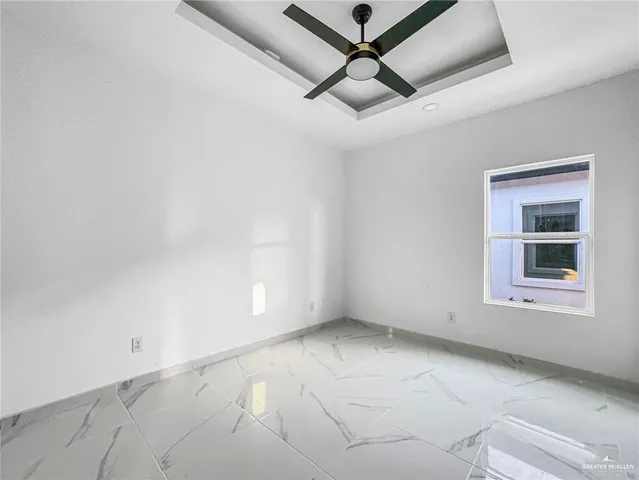 an empty room with a ceiling fan and windows