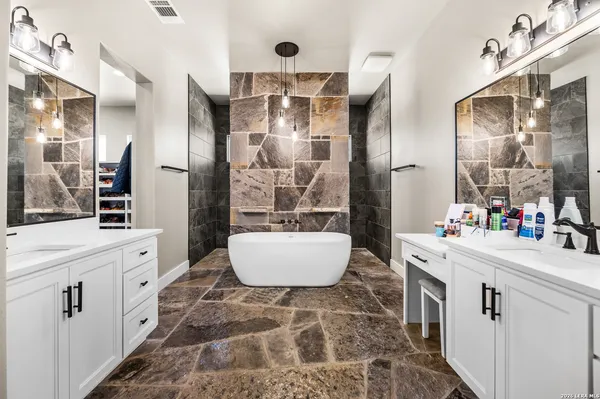a bathroom with a double vanity sink mirror and bathtub