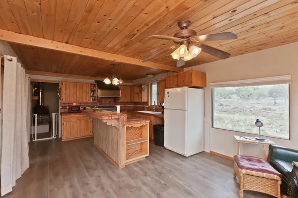 a kitchen with stainless steel appliances granite countertop a refrigerator a sink dishwasher a stove and white countertops with wooden floor