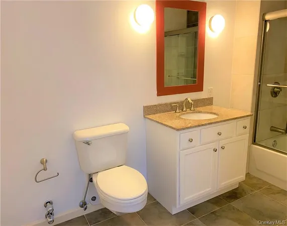 a bathroom with a granite countertop toilet sink and mirror