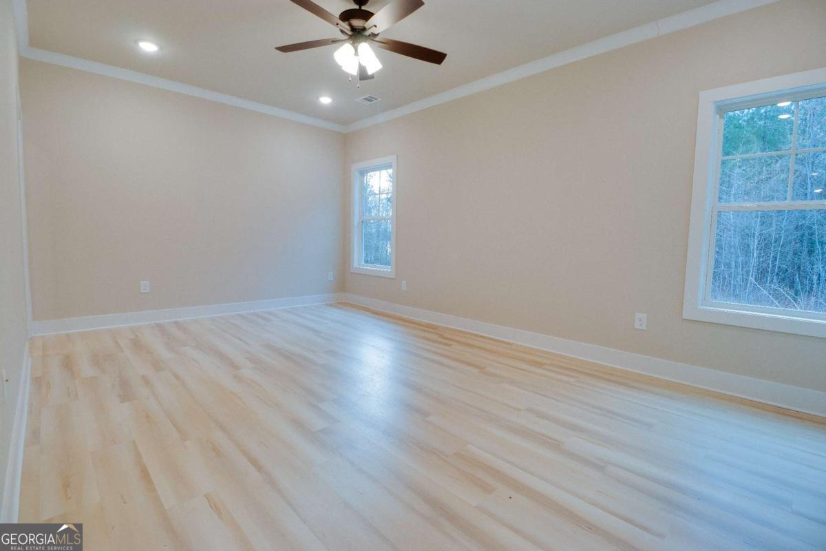 1021 Pointe Street South Tignall, GA 30668 - Photo 16 of 48 an empty room with wooden floor fan and windows