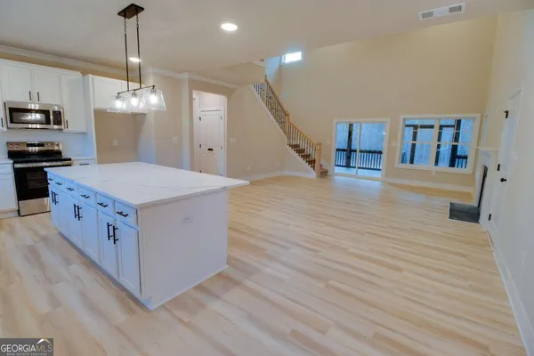 a kitchen with stainless steel appliances kitchen island wooden floors granite counter tops and white cabinets