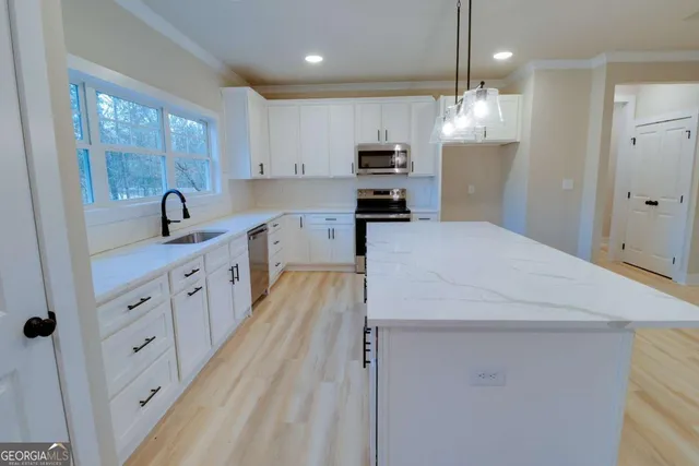 a kitchen with granite countertop a sink cabinets a counter top space and stainless steel appliances