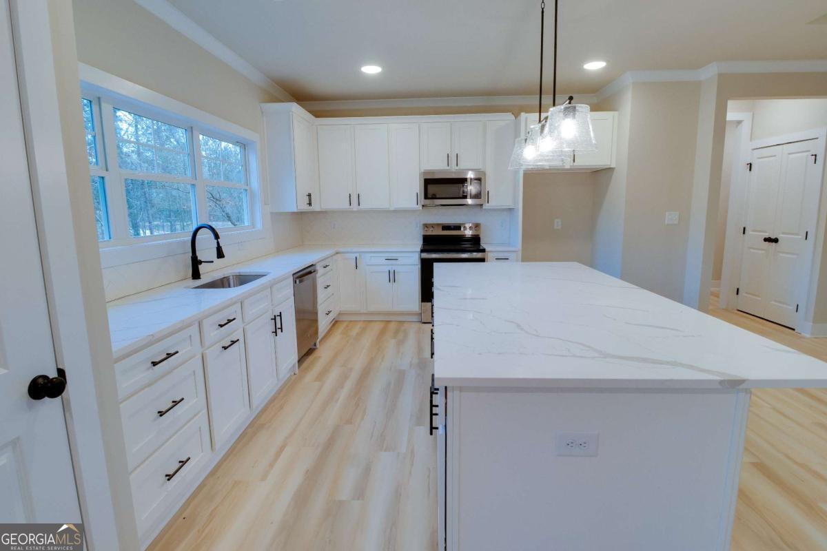 1021 Pointe Street South Tignall, GA 30668 - Photo 7 of 48 a kitchen with kitchen island granite countertop a sink a counter space appliances and cabinets