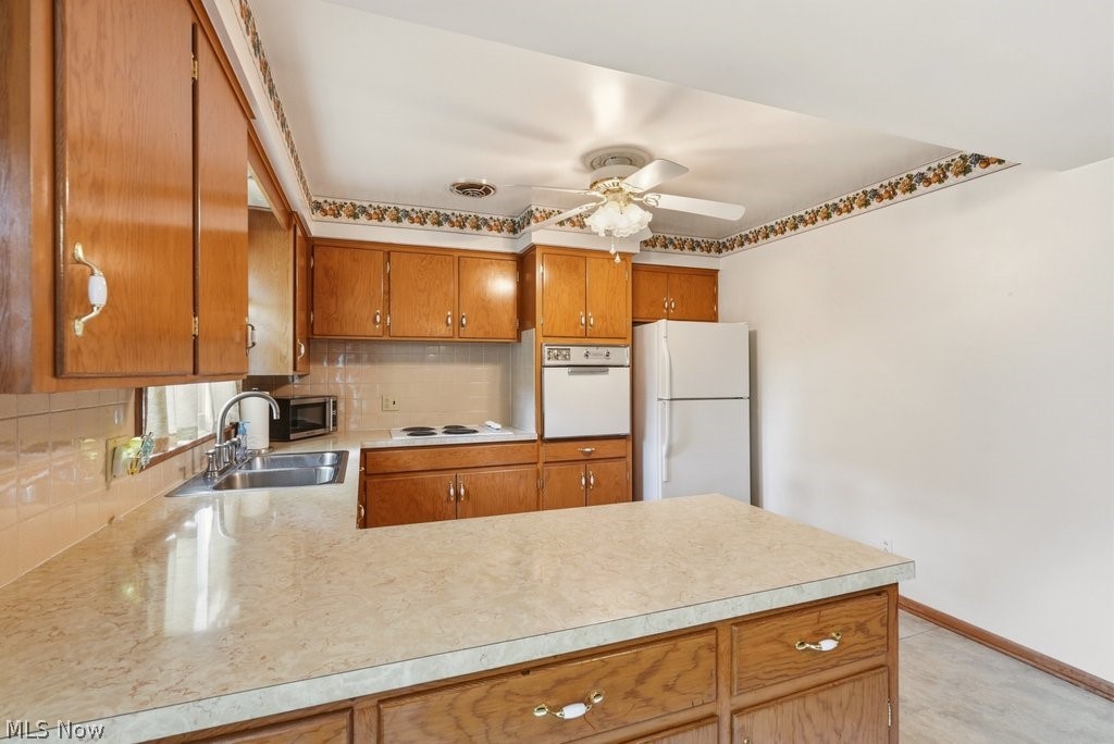 161 Pinehurst Road Munroe Falls, OH 44262 - Photo 13 of 40 Kitchen featuring wood cabinetry, solid surface countertops, a double basin stainless steel sink, a built-in electric range, and a ceiling fan with integrated lighting