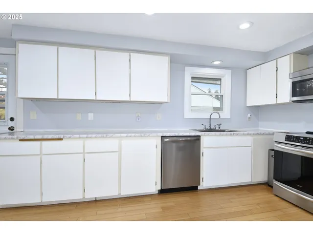 a kitchen with granite countertop white cabinets sink and stainless steel appliances