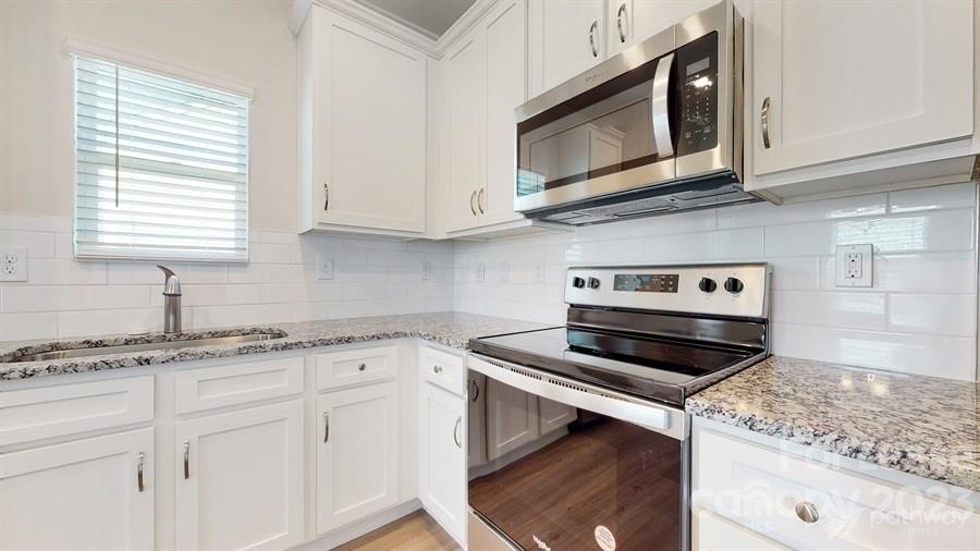 163 Tanner Loop Troutman, NC 28166 - Photo 11 of 27 a kitchen with granite countertop cabinets stainless steel appliances and a sink