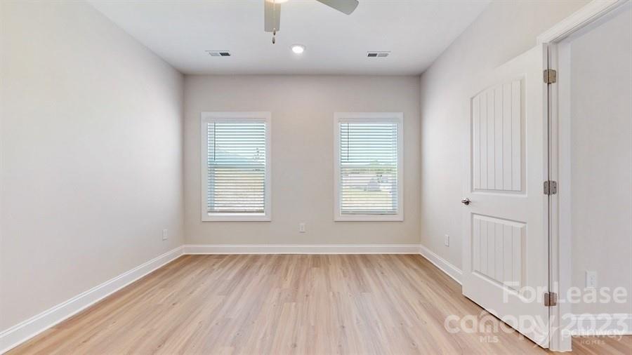 163 Tanner Loop Troutman, NC 28166 - Photo 18 of 27 an empty room with wooden floor and windows